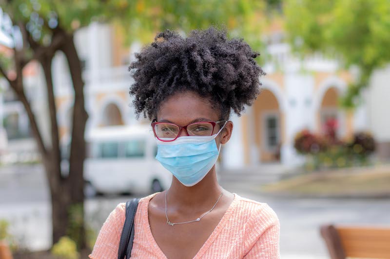 Girl in facial mask standing in front of an SGU building wearing a pink shirt