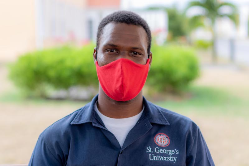 Man wearing protective mask in an SGU shirt smiling at camera