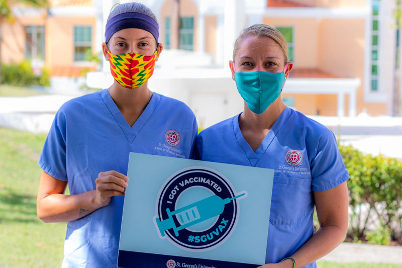 Woman in a mask holding a sign that shows she got her COVID vaccine