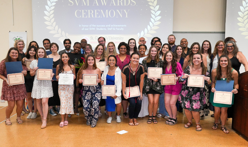 SVM students and faculty stand together as a group posing with their awards. 