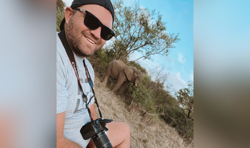 Dr. Schutte in the outdoors with an elephant behind him