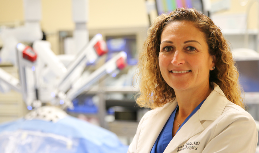 Andrea Pakula standing in front of robotic surgery equipment