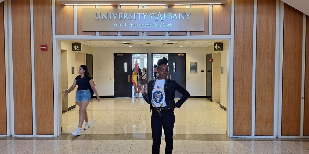 Alanda Joseph, a new Fulbright Scholar, standing in front of "University at Albany" sign 